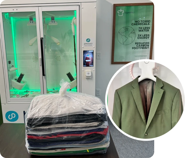 A stack of folded clothes wrapped in plastic sits in front of a garment cleaning machine, with an inset of a green suit jacket on a hanger.